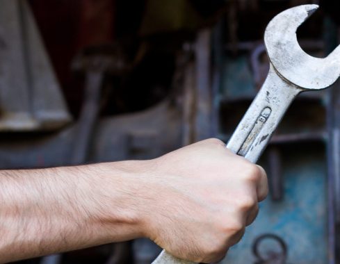 Hand holding wrench on dark background
